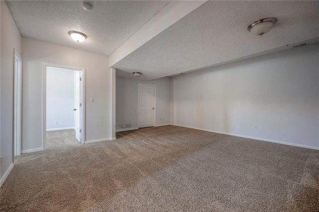 carpeted empty room featuring a textured ceiling, visible vents, and baseboards