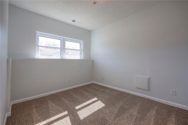 unfurnished room with a textured ceiling, carpet flooring, visible vents, and baseboards