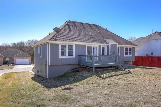 back of property with a yard, a shingled roof, fence, and a wooden deck