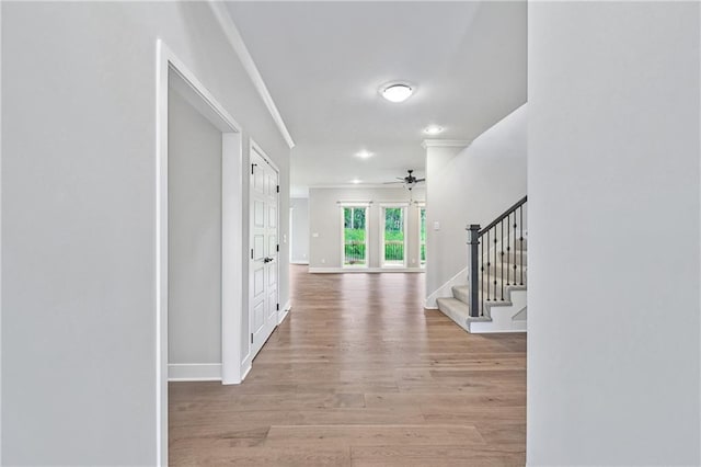 foyer featuring baseboards, a ceiling fan, ornamental molding, wood finished floors, and stairs