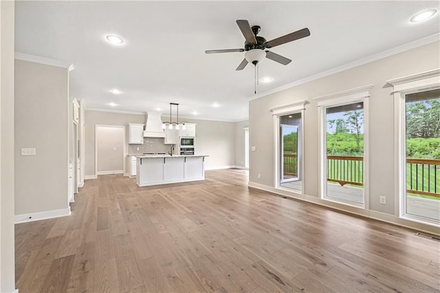 unfurnished living room featuring baseboards, light wood-style flooring, visible vents, and crown molding