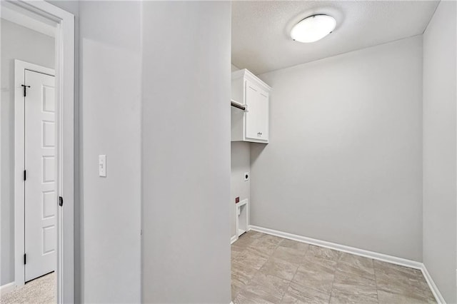 laundry area with baseboards, a textured ceiling, cabinet space, and electric dryer hookup