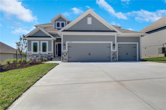 7009 NE 103rd St, Kansas City, MO 64156 - craftsman inspired home featuring an attached garage, stone siding, driveway, and a front yard