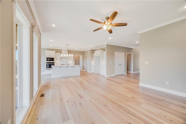 7009 NE 103rd St, Kansas City, MO 64156 - unfurnished living room featuring crown molding, a ceiling fan, light wood-style floors, and recessed lighting