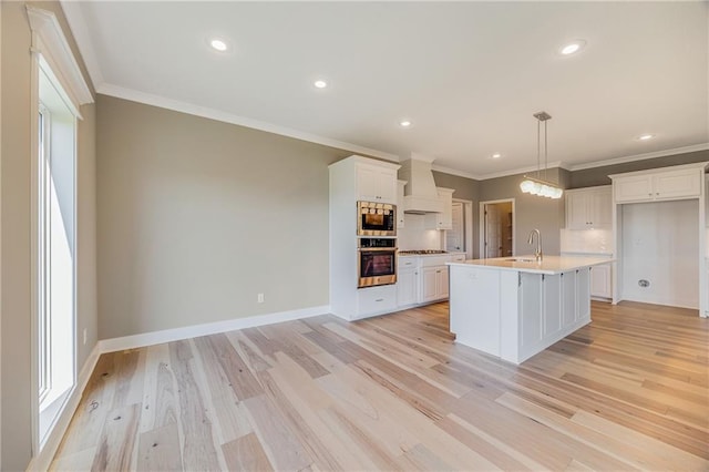 7009 NE 103rd St, Kansas City, MO 64156 - kitchen with appliances with stainless steel finishes, custom range hood, white cabinetry, crown molding, and light wood-style flooring