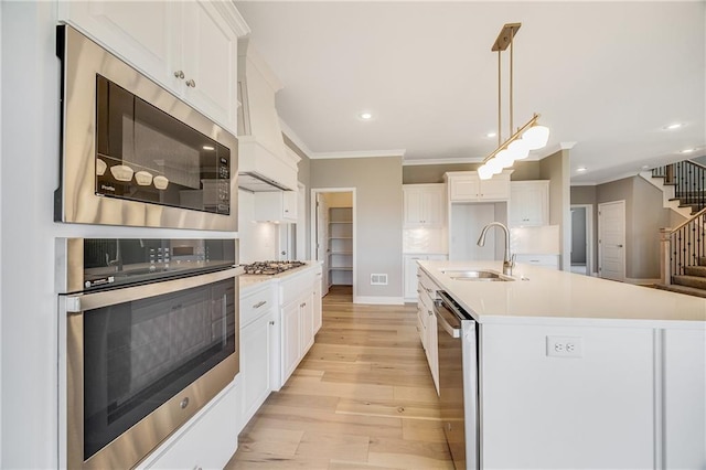 7009 NE 103rd St, Kansas City, MO 64156 - kitchen featuring stainless steel appliances, ornamental molding, light wood-style flooring, white cabinets, and light countertops