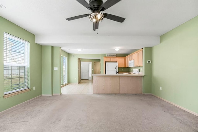 unfurnished living room with baseboards, a ceiling fan, visible vents, and light colored carpet