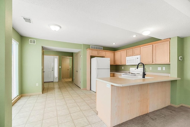 kitchen featuring light countertops, white appliances, visible vents, and a peninsula