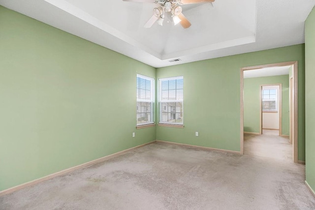 unfurnished room featuring baseboards, carpet floors, a raised ceiling, and a healthy amount of sunlight