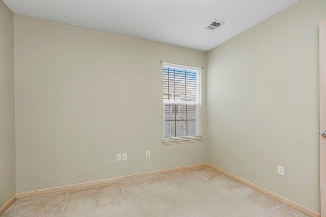 carpeted spare room featuring baseboards and visible vents