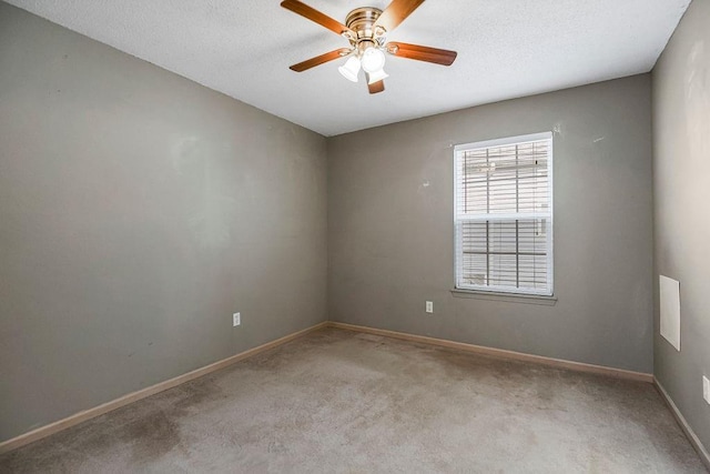 spare room with carpet floors, a textured ceiling, baseboards, and a ceiling fan