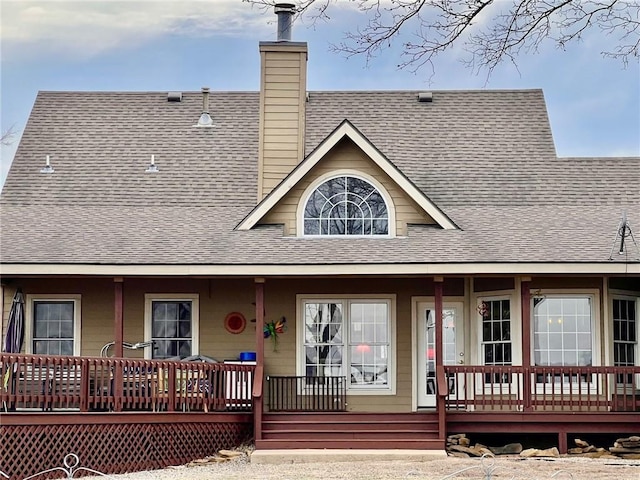 exterior space with a porch, a shingled roof, and a chimney