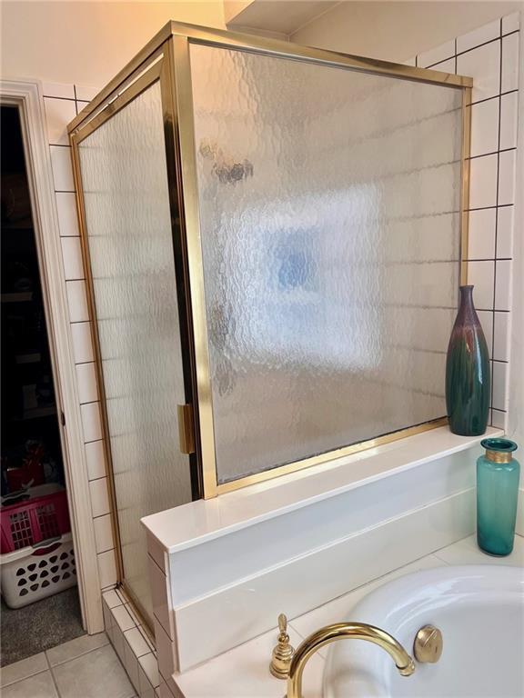 bathroom with tile patterned flooring, a bath, and a shower stall