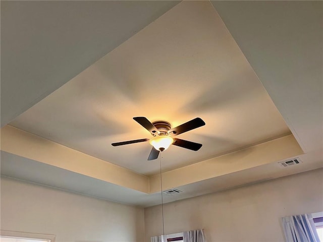 details featuring a tray ceiling, visible vents, and ceiling fan