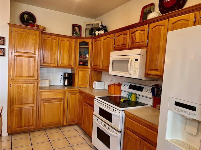 kitchen with tasteful backsplash, white appliances, brown cabinets, and light tile patterned floors