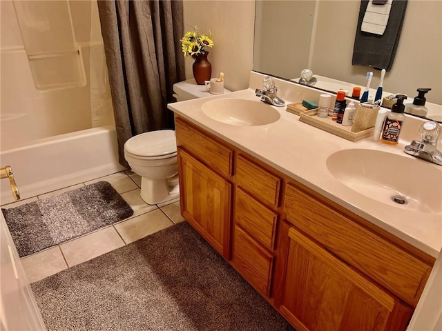 bathroom with double vanity, a sink, toilet, and tile patterned floors