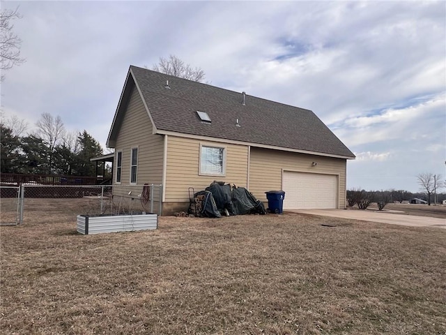 back of property featuring a garage, a shingled roof, fence, and a lawn