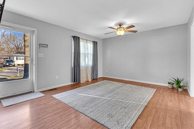 interior space with visible vents, ceiling fan, baseboards, and wood finished floors