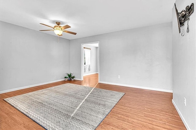 spare room with baseboards, a ceiling fan, and wood finished floors