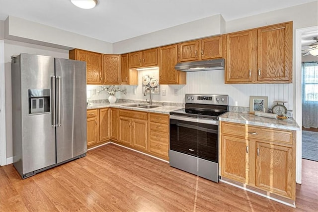 kitchen with a sink, stainless steel appliances, light countertops, under cabinet range hood, and light wood-type flooring