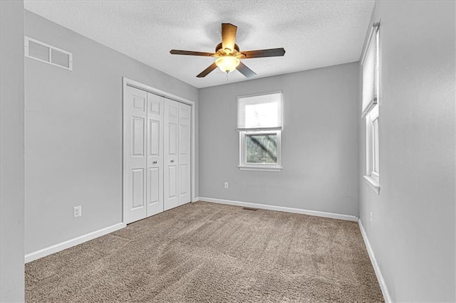 unfurnished bedroom with visible vents, baseboards, carpet, a closet, and a textured ceiling