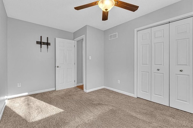 unfurnished bedroom with visible vents, a closet, carpet flooring, baseboards, and ceiling fan