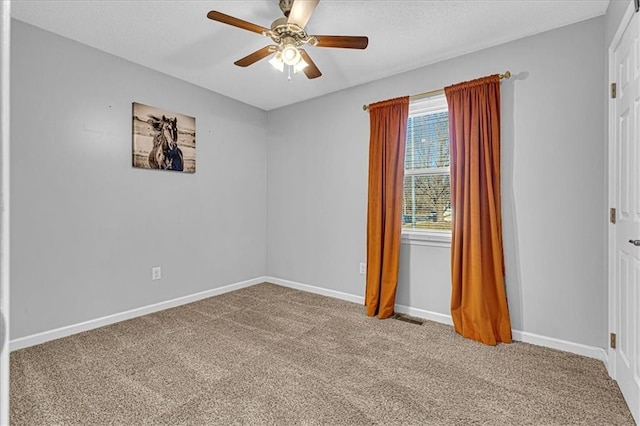 carpeted spare room with a textured ceiling, visible vents, baseboards, and ceiling fan