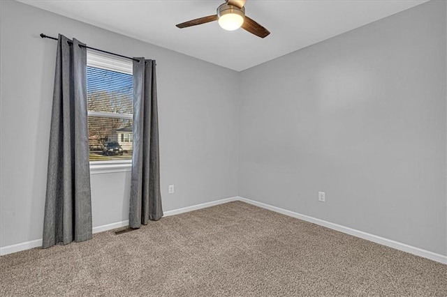 carpeted spare room featuring visible vents, baseboards, and ceiling fan