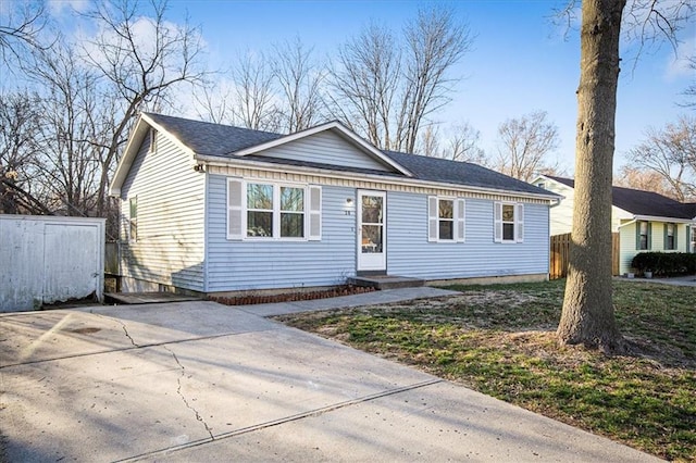 view of front of home featuring driveway, roof with shingles, and fence