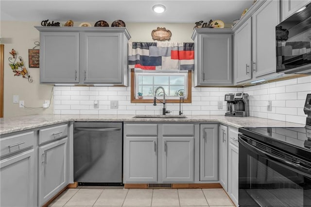 kitchen featuring backsplash, gray cabinetry, light tile patterned flooring, a sink, and black appliances