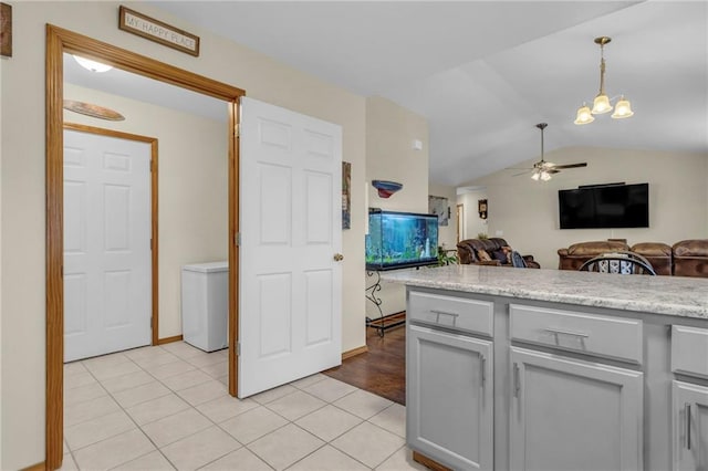 kitchen with light tile patterned floors, lofted ceiling, gray cabinetry, open floor plan, and light countertops