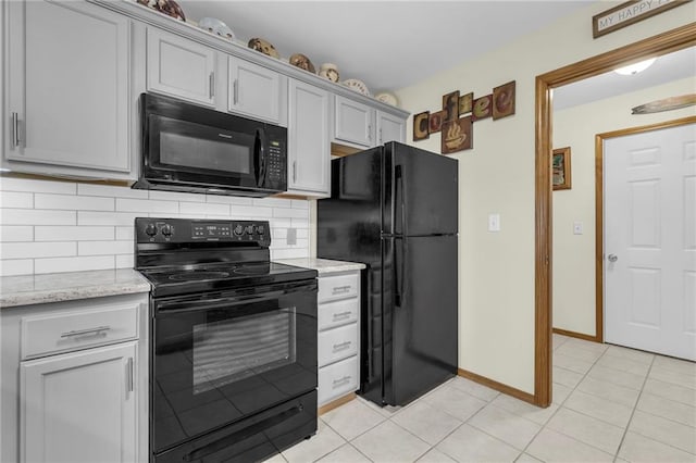 kitchen featuring tasteful backsplash, baseboards, light stone counters, black appliances, and light tile patterned flooring