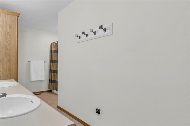 bathroom featuring a shower with curtain, baseboards, and a sink