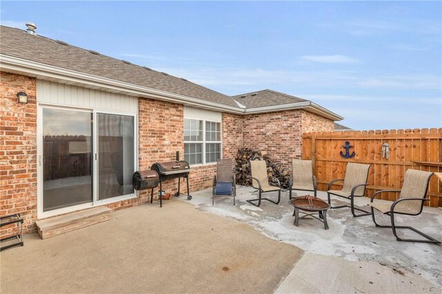 view of patio with a fire pit, a grill, and fence