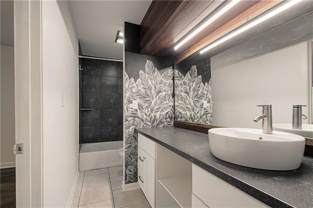 bathroom featuring tile patterned flooring, toilet, vanity, baseboards, and shower / washtub combination