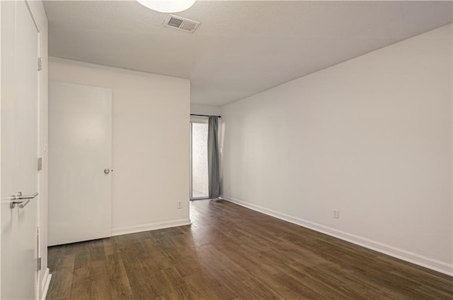 unfurnished bedroom featuring dark wood finished floors, visible vents, and baseboards