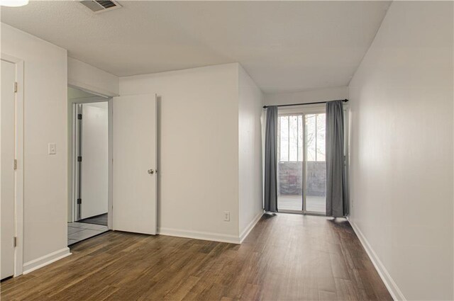 spare room featuring baseboards, visible vents, and dark wood-type flooring