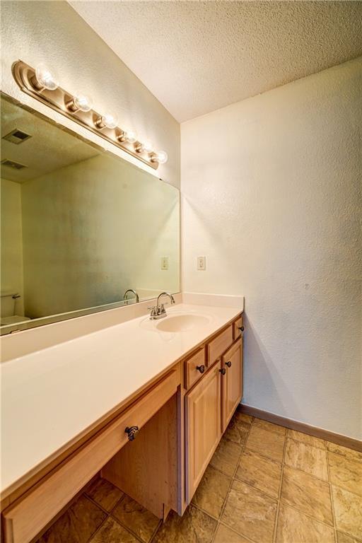 bathroom featuring vanity, toilet, baseboards, and a textured ceiling