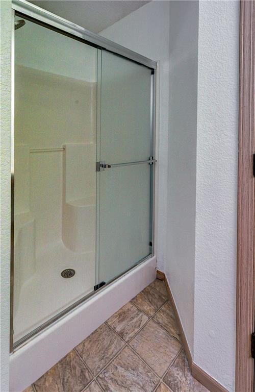 bathroom with a stall shower, baseboards, and a textured wall