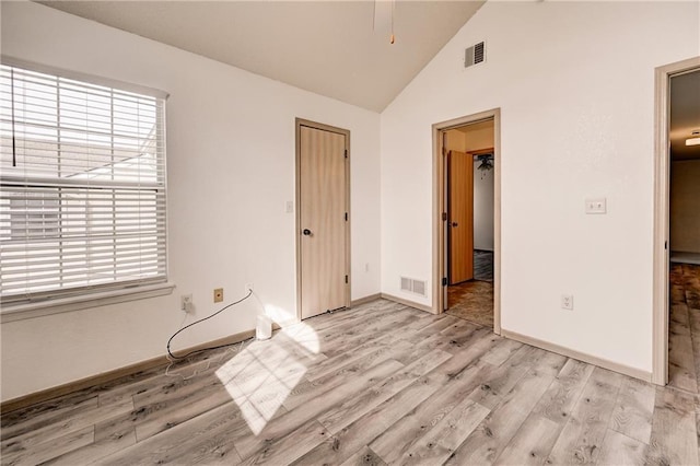 unfurnished bedroom featuring light wood-style flooring, baseboards, visible vents, and high vaulted ceiling