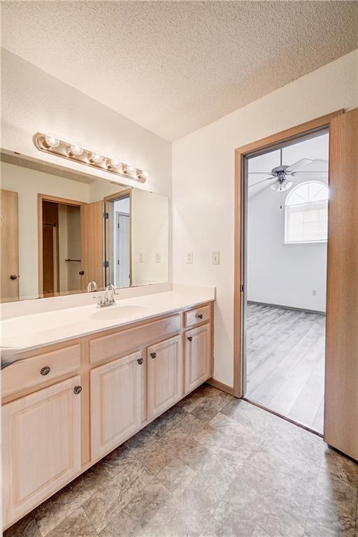 bathroom featuring a textured ceiling, vanity, and a ceiling fan