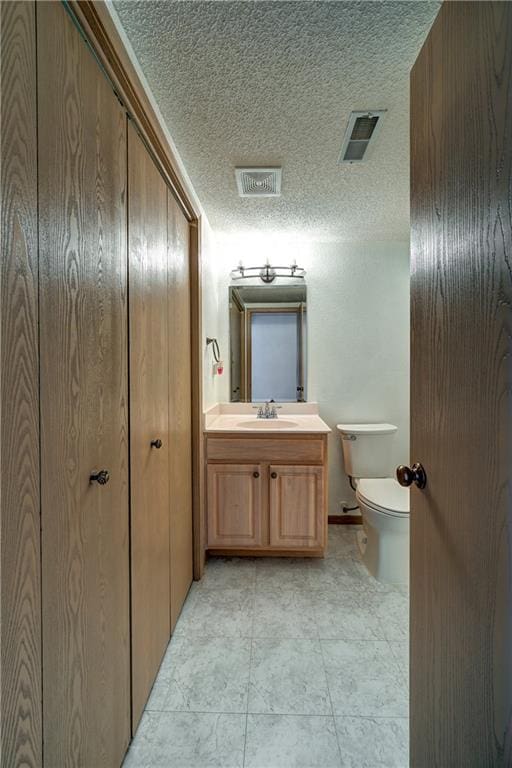 bathroom featuring vanity, toilet, and a textured ceiling