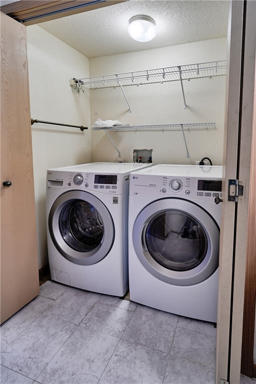 washroom featuring washing machine and clothes dryer, laundry area, and a textured ceiling