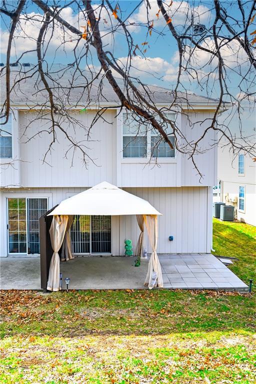 back of property featuring central air condition unit, a lawn, and a patio area