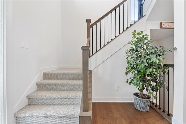 staircase featuring baseboards and wood finished floors