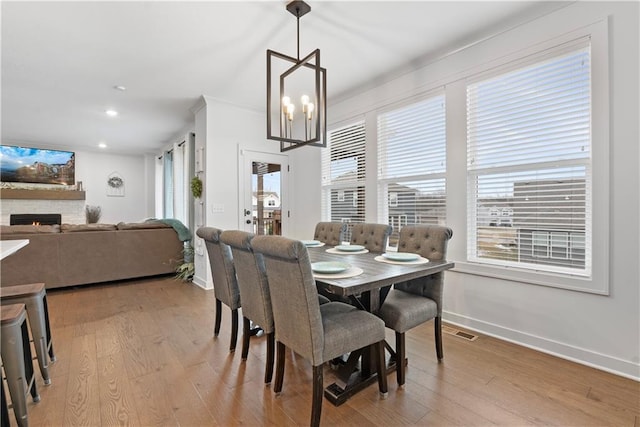 dining room featuring light wood finished floors, visible vents, plenty of natural light, and a fireplace