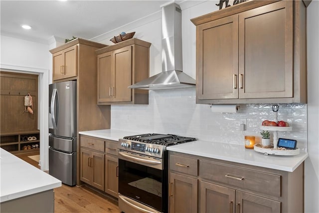 kitchen with light wood-type flooring, backsplash, appliances with stainless steel finishes, wall chimney exhaust hood, and light countertops