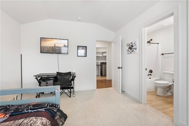 carpeted bedroom with baseboards, ensuite bathroom, and vaulted ceiling