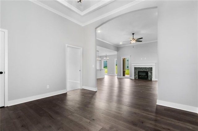 unfurnished living room with baseboards, dark wood-type flooring, crown molding, and ceiling fan with notable chandelier