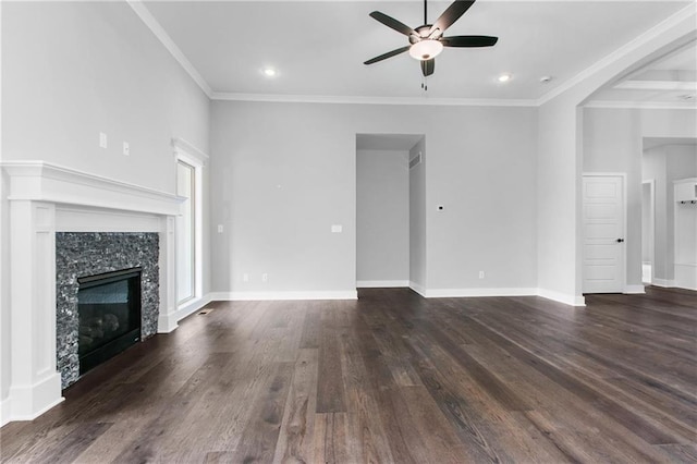 unfurnished living room with a tile fireplace, dark wood-style flooring, a ceiling fan, baseboards, and crown molding